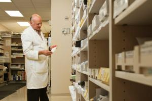 pharmacist standing near brown wooden shelf