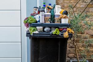 black trash bin with green leaves